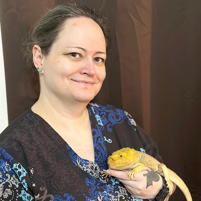 Kelly smiling and holding a bearded dragon in her hands.